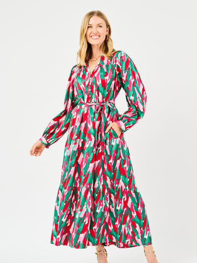 Woman wearing a colorful patterned holiday dress with pinks, greens, reds and whites on a white background