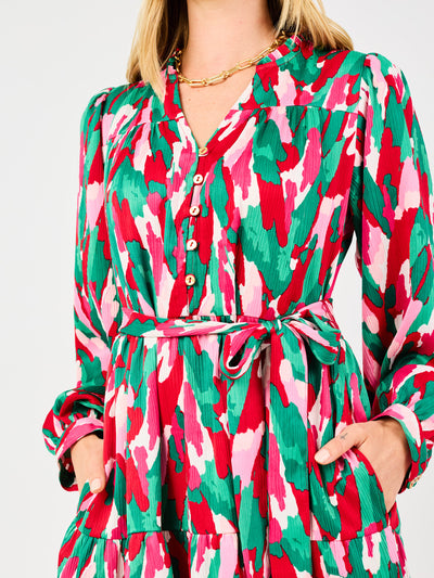 Woman wearing a colorful patterned holiday dress with pinks, greens, reds and whites on a white background