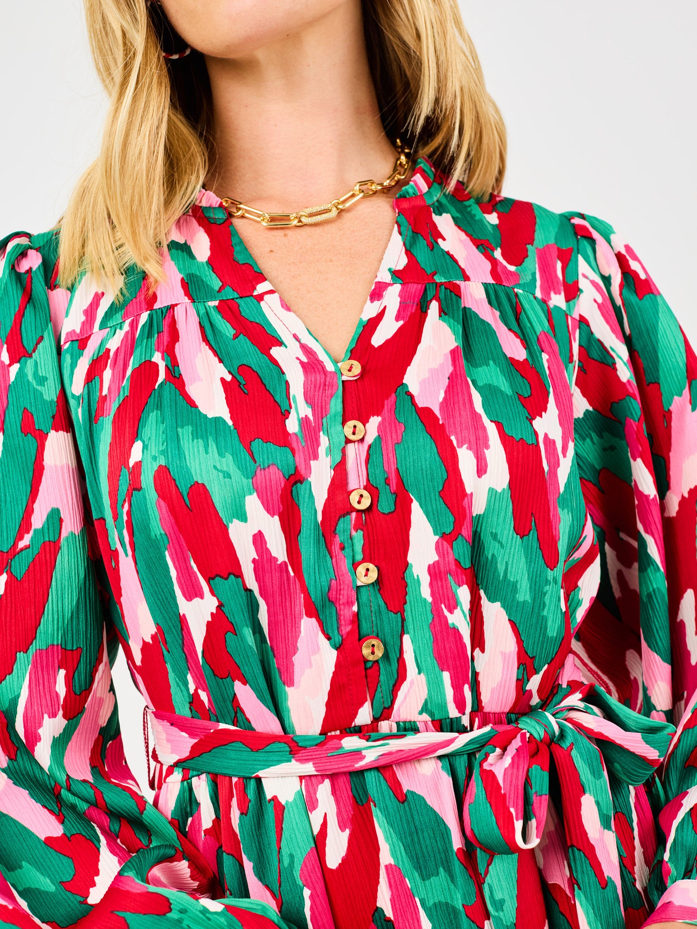 Close-up of a person wearing a colorful patterned dress with a gold necklace.