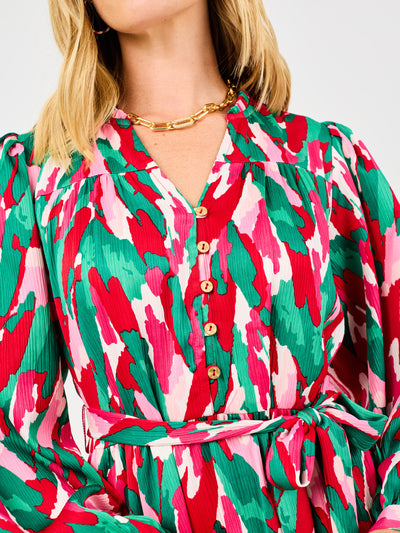 Close-up of a person wearing a colorful patterned dress with a gold necklace.