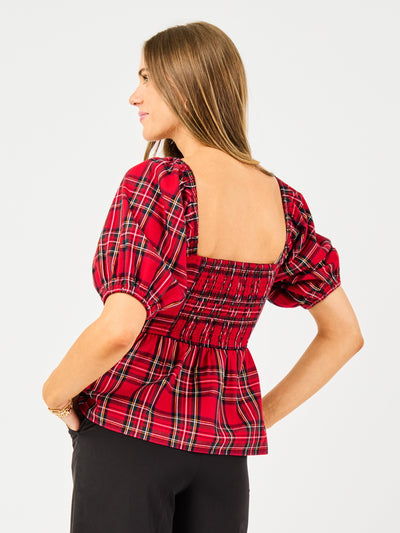 Woman wearing a red plaid top with puff sleeves on a white background