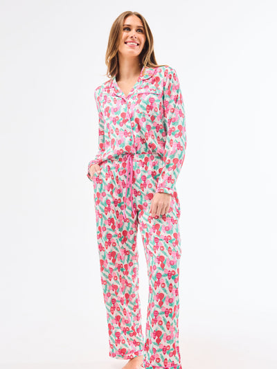 Woman wearing a christmas pajama set  with holiday ornaments in pinks, greens and reds on a white background