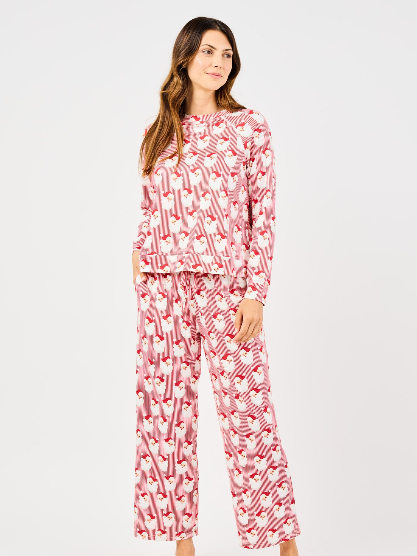 Woman wearing a red santa and striped patterned pajama set on a white background