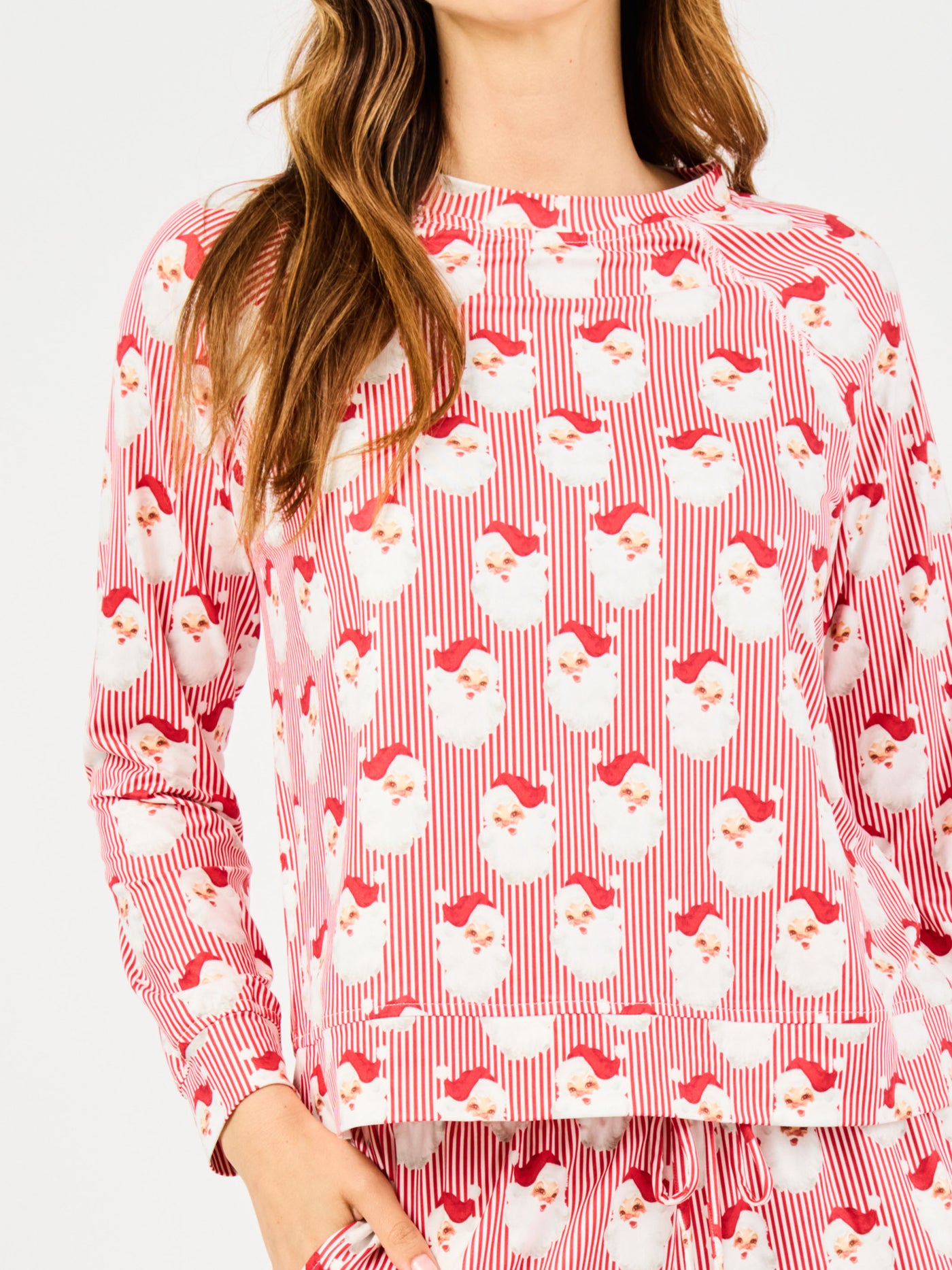 Woman wearing a red santa claus and striped patterned pajama set on a white background