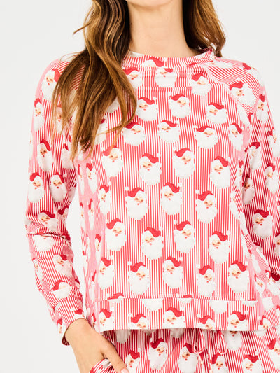 Woman wearing a red santa claus and striped patterned pajama set on a white background