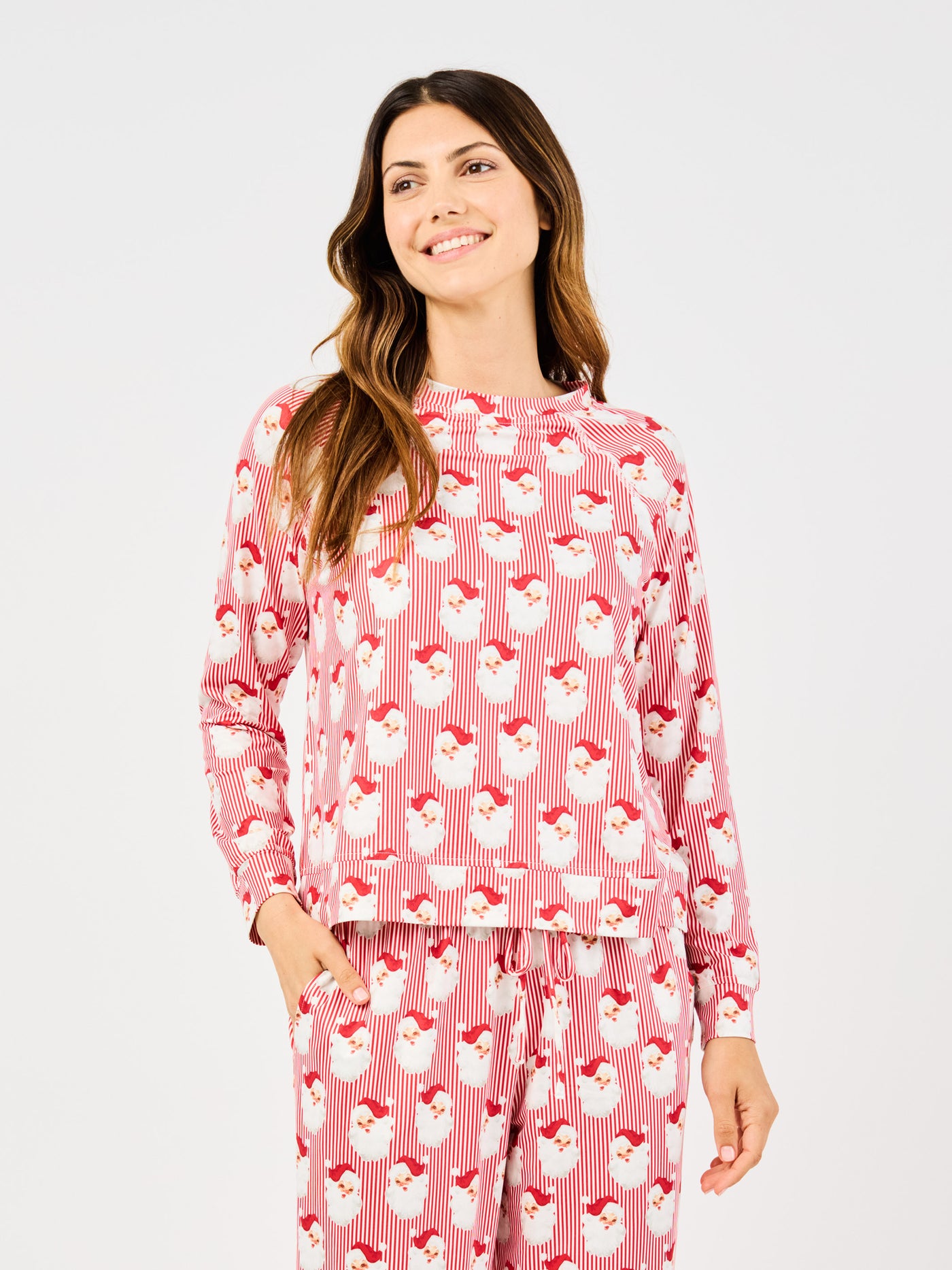 Woman wearing a red santa claus and striped patterned pajama set on a white background