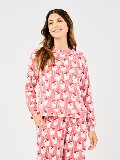 Woman wearing a red santa claus and striped patterned pajama set on a white background