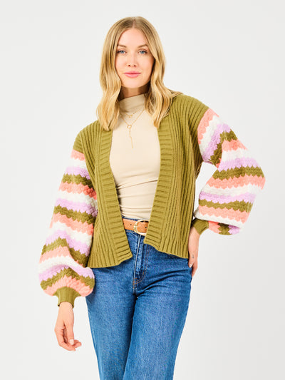 Woman wearing a green cardigan with colorful sleeves on a white background