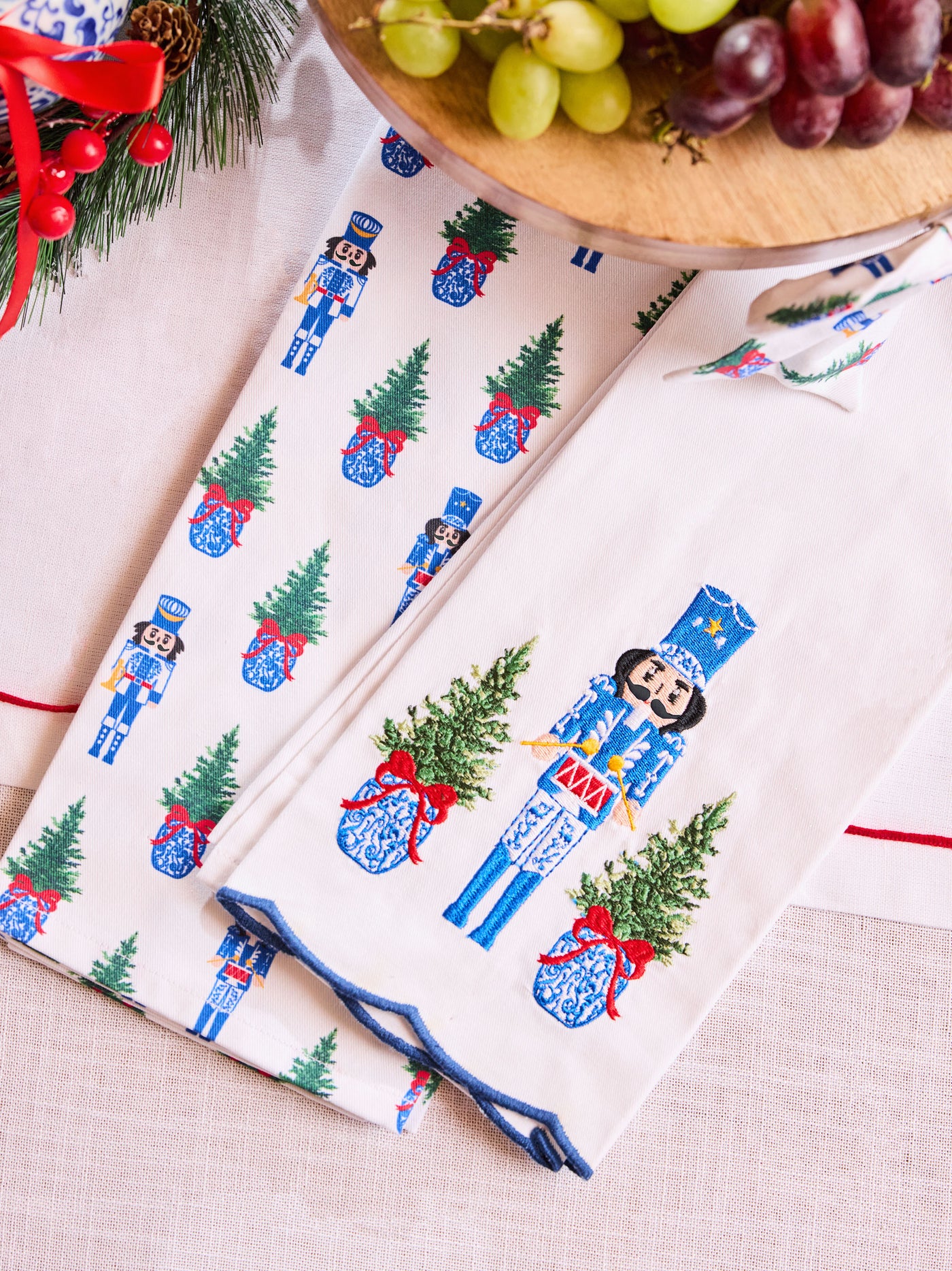 Tea towels with Christmas-themed design featuring nutcrackers and trees on a table.