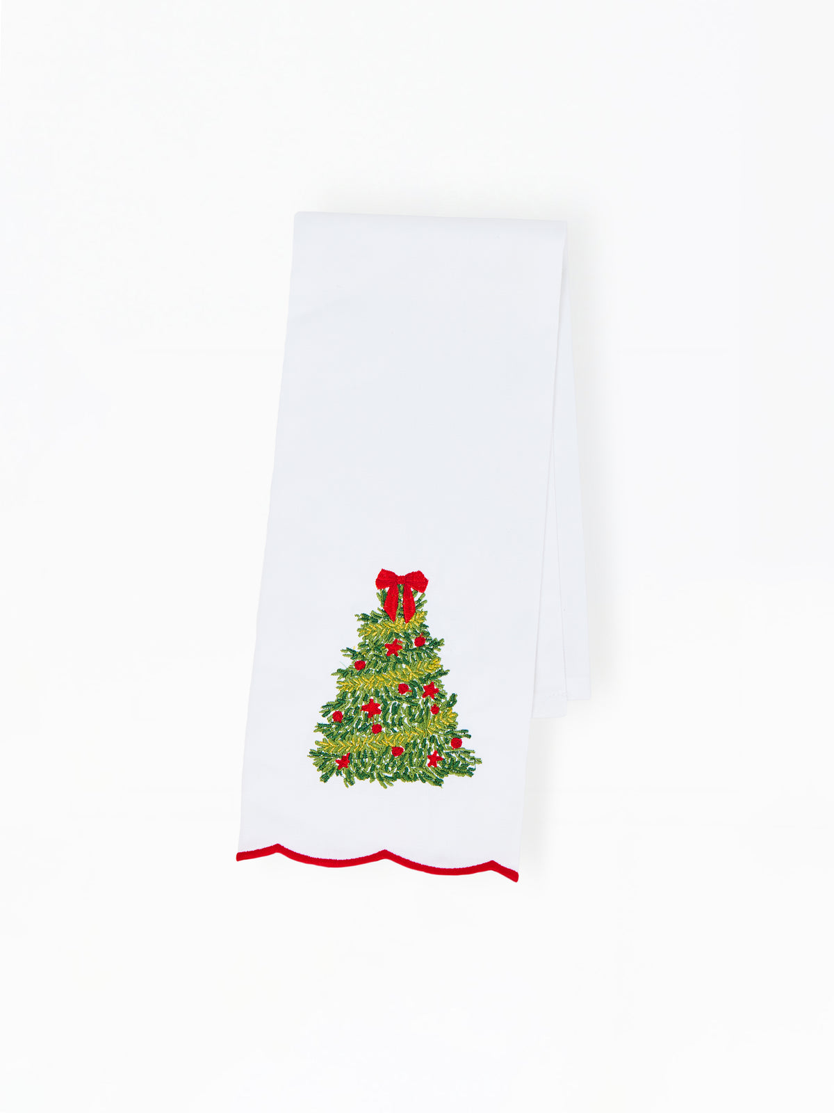 A white kitchen towel featuring a green holly and mistletoe Christmas tree design with red ornaments and a red bow, finished with a red scalloped hem.