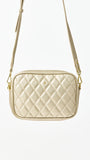 Quilted beige handbag with gold chain strap on a white background