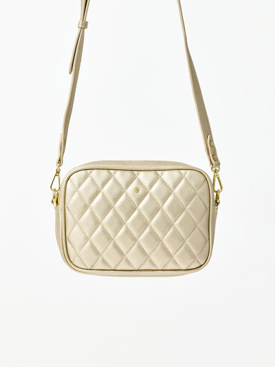 Quilted beige handbag with gold chain strap on a white background