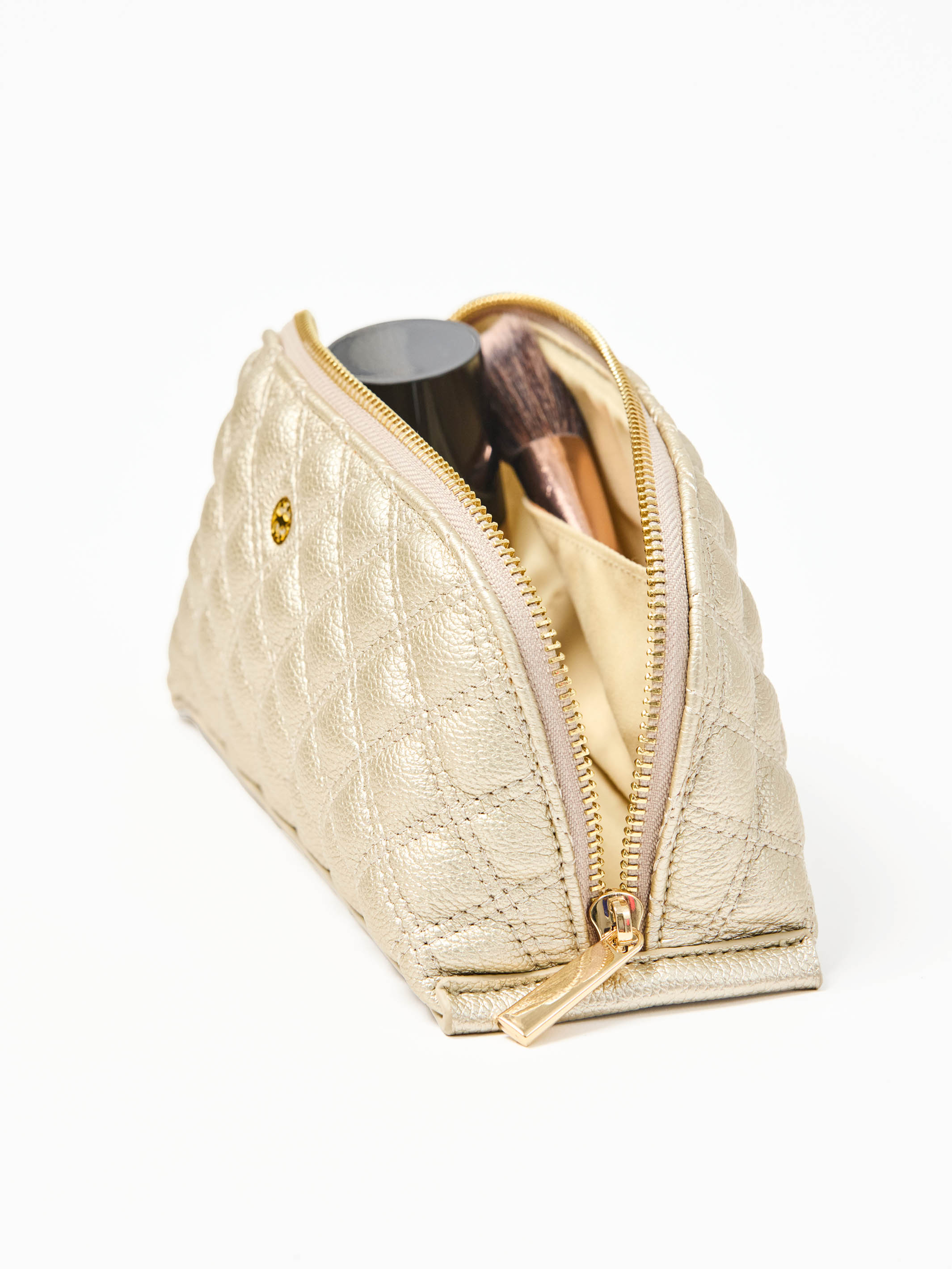 Gold makeup pouch with cosmetic items on a white background