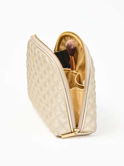 Quilted champagne colored cosmetic bag on a white background