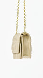 Champagne colored quilted handbag with gold chain strap on a white background