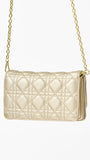 Champagne colored quilted handbag with gold chain strap on a white background