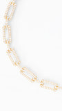 A gold-tone chain necklace with elongated rectangular links paved with small clear stones, photographed on a clean white background.