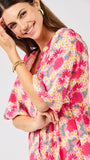 Woman wearing a  pink floral midi dress on a white background