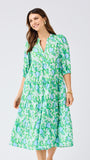 Woman wearing a green floral dress on a light gray background