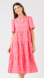 Woman wearing a pink patterned dress on a light gray background