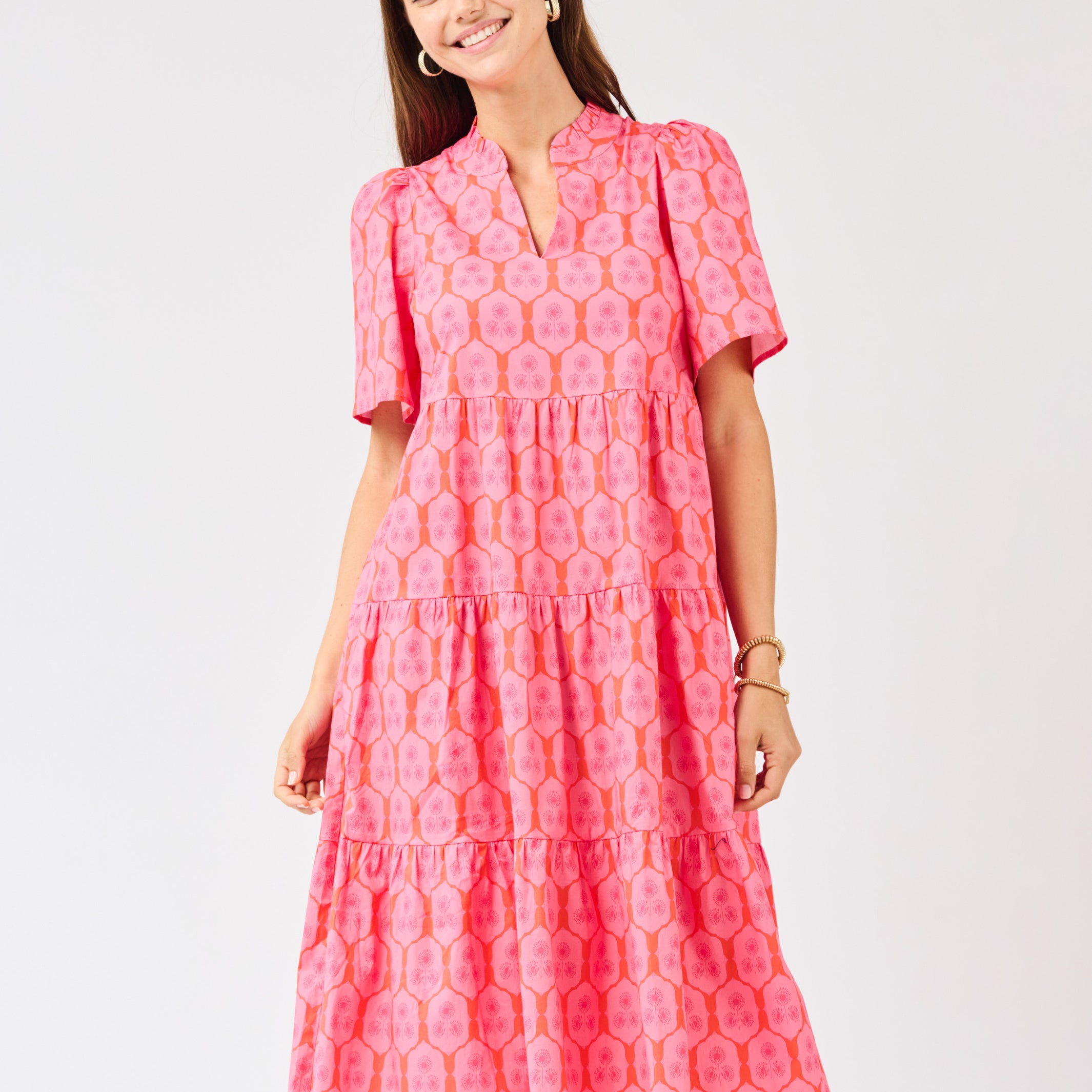 Woman wearing a pink patterned dress on a light gray background