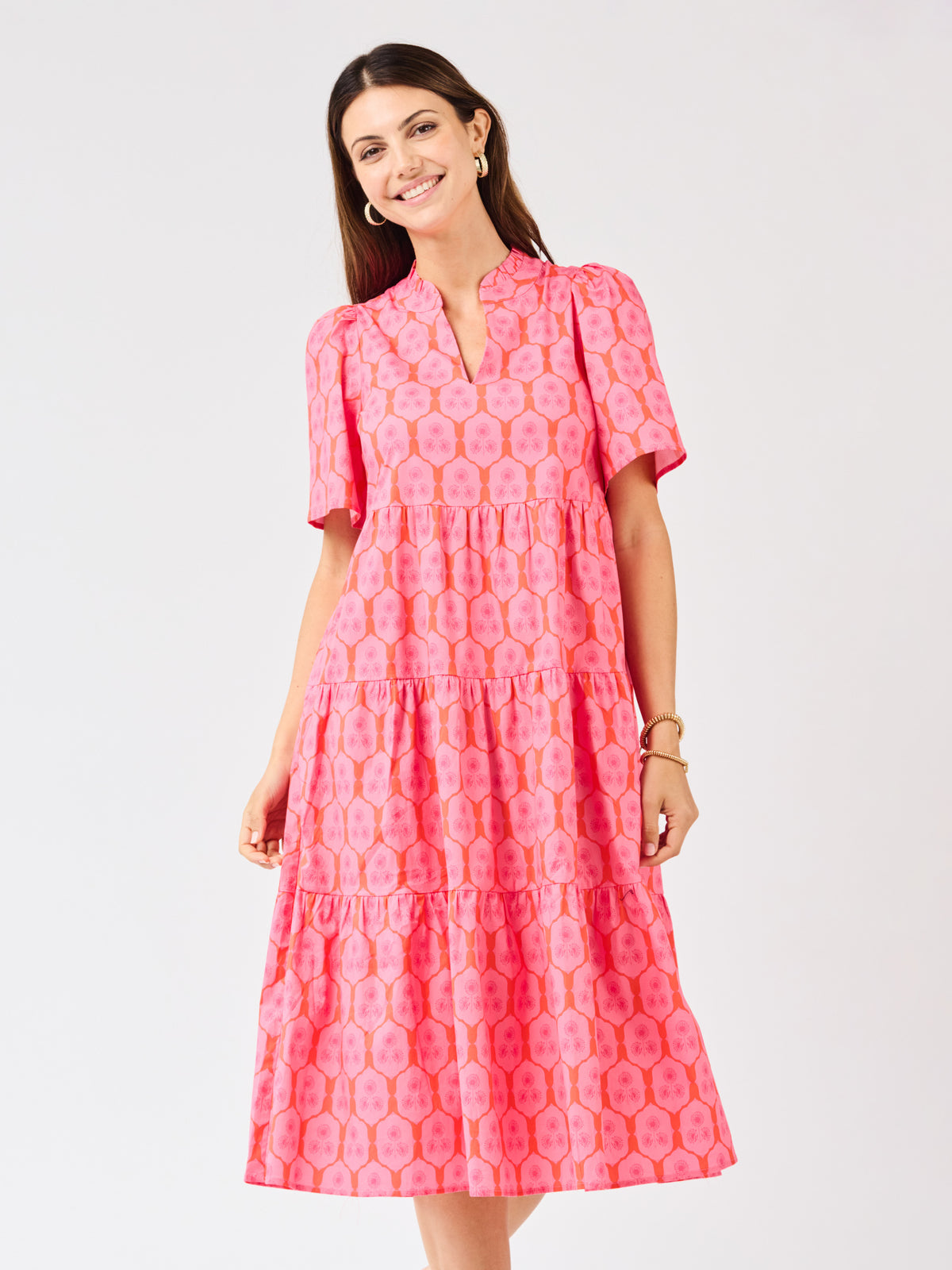Woman wearing a pink patterned dress on a light gray background