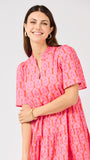 Woman wearing a pink and orange patterned dress on a white background