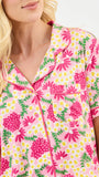 Woman wearing a pink floral patterned shirt with a white background