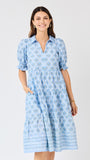 Woman wearing a blue patterned dress on a light gray background