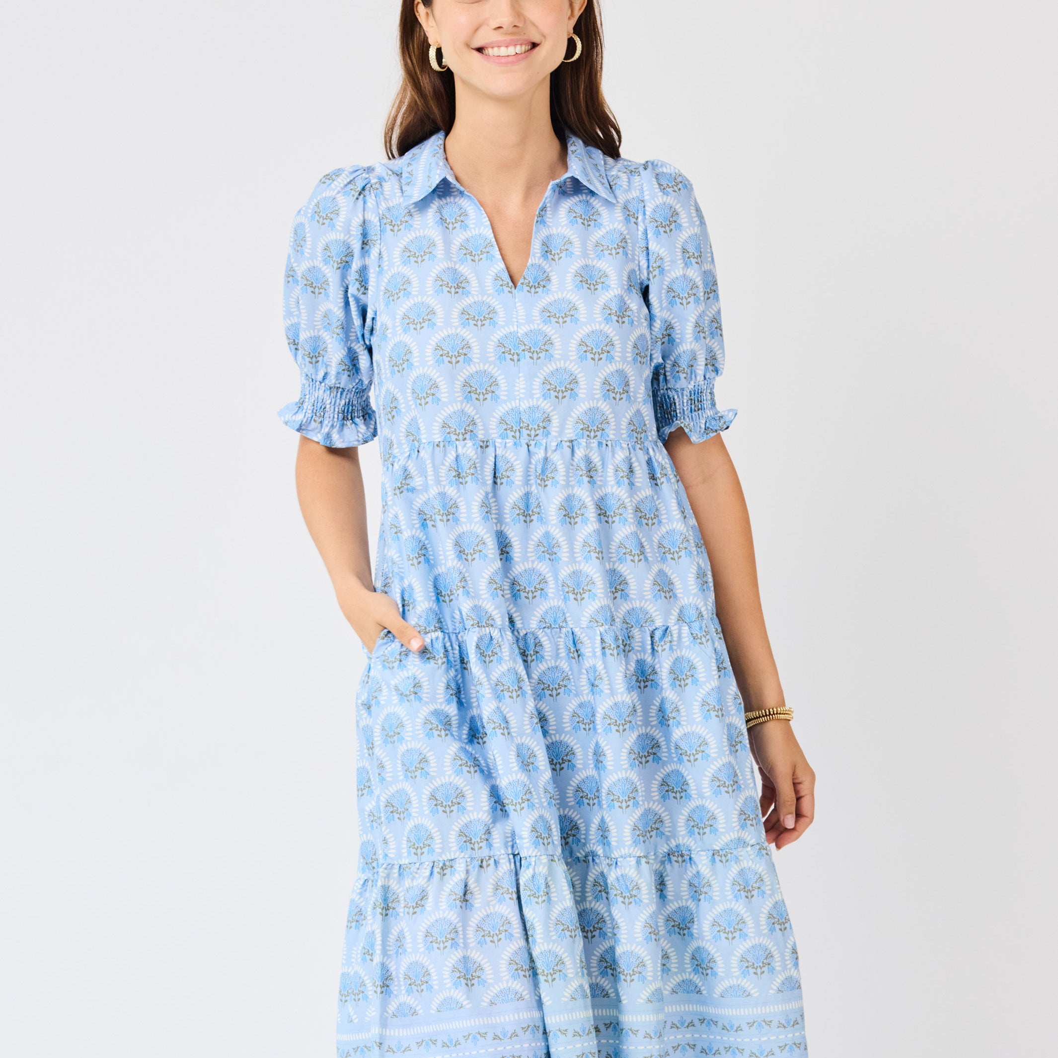 Woman wearing a blue patterned dress on a light gray background