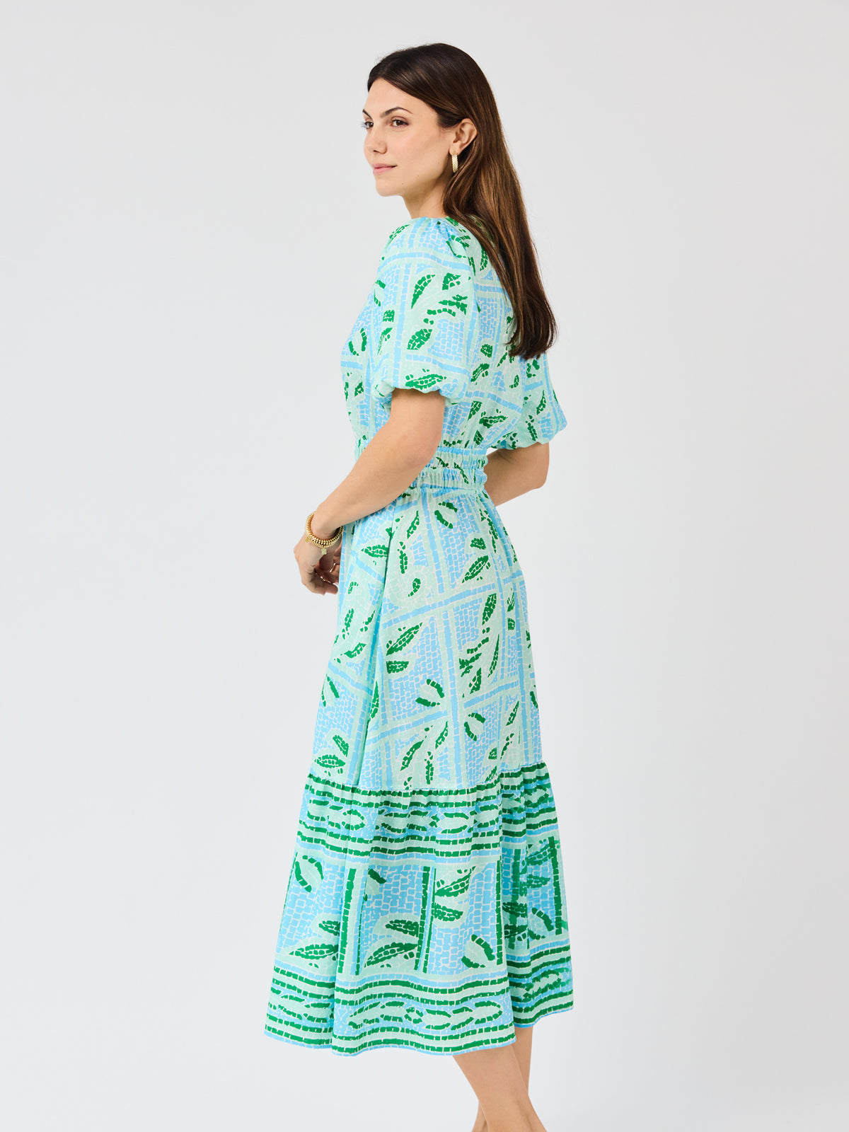 Woman wearing a blue and green patterned dress on a white background