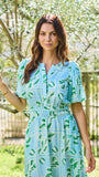 Woman wearing a light blue dress with green leaf pattern outdoors