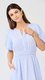 Woman wearing a light blue seersucker midi dress with puff sleeves a white background