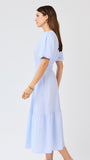 Woman wearing a light blue seersucker midi dress with puff sleeves a white background