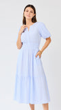 Woman wearing a light blue seersucker midi dress with puff sleeves a white background