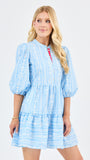 Woman wearing a light blue floral dress with white patterns on a white background