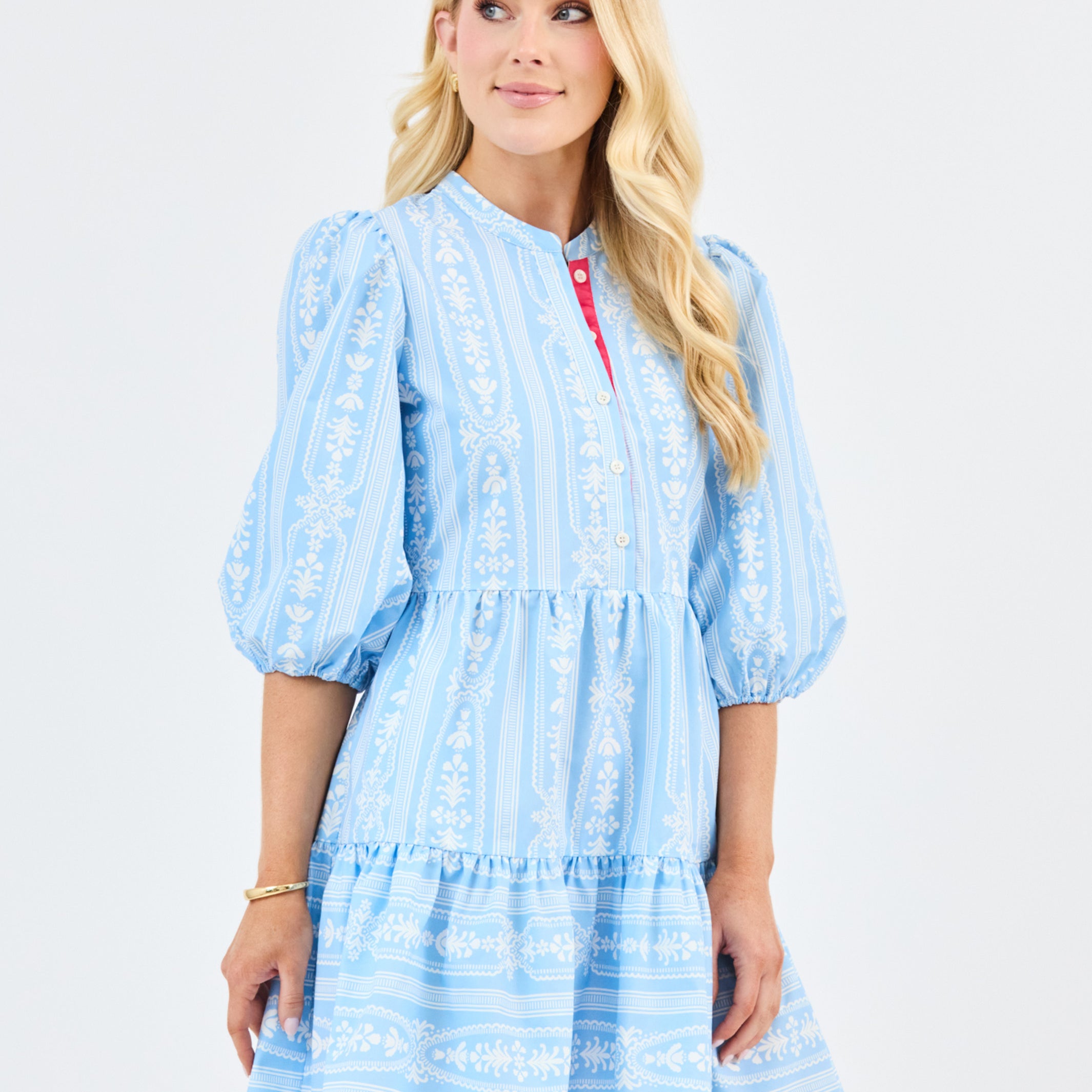 Woman wearing a light blue floral dress with white patterns on a white background