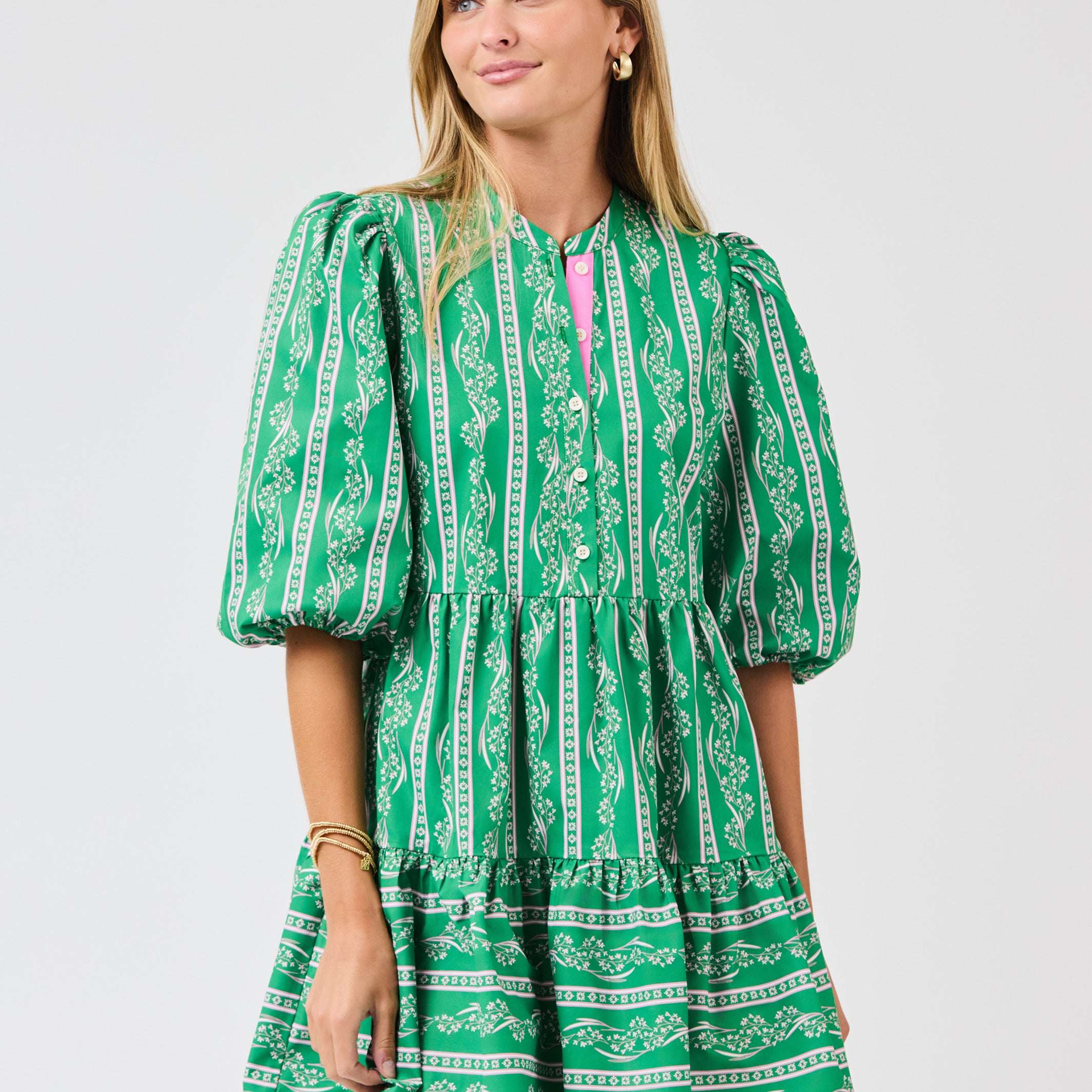 Woman wearing a green patterned dress on a light gray background