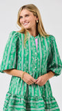 Woman wearing a green patterned dress on a plain background