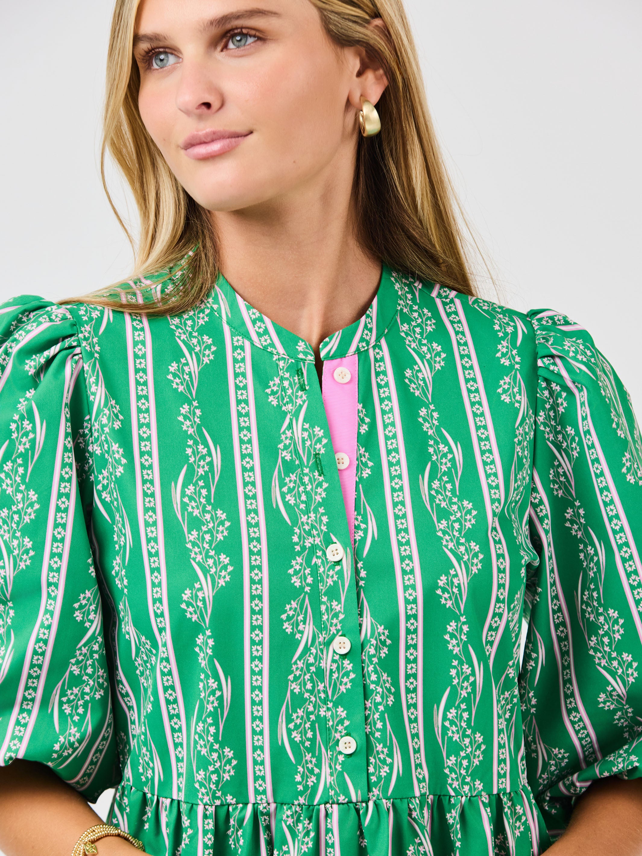 Woman wearing a green patterned dress with a white background