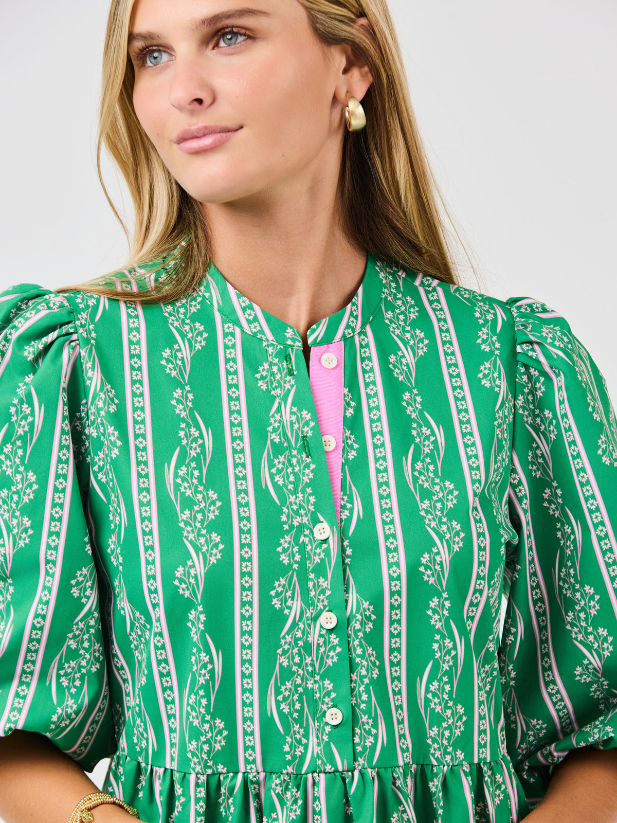 Woman wearing a green patterned dress with a white background