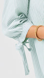 Green and white striped shirt with a tie detail on a light gray background