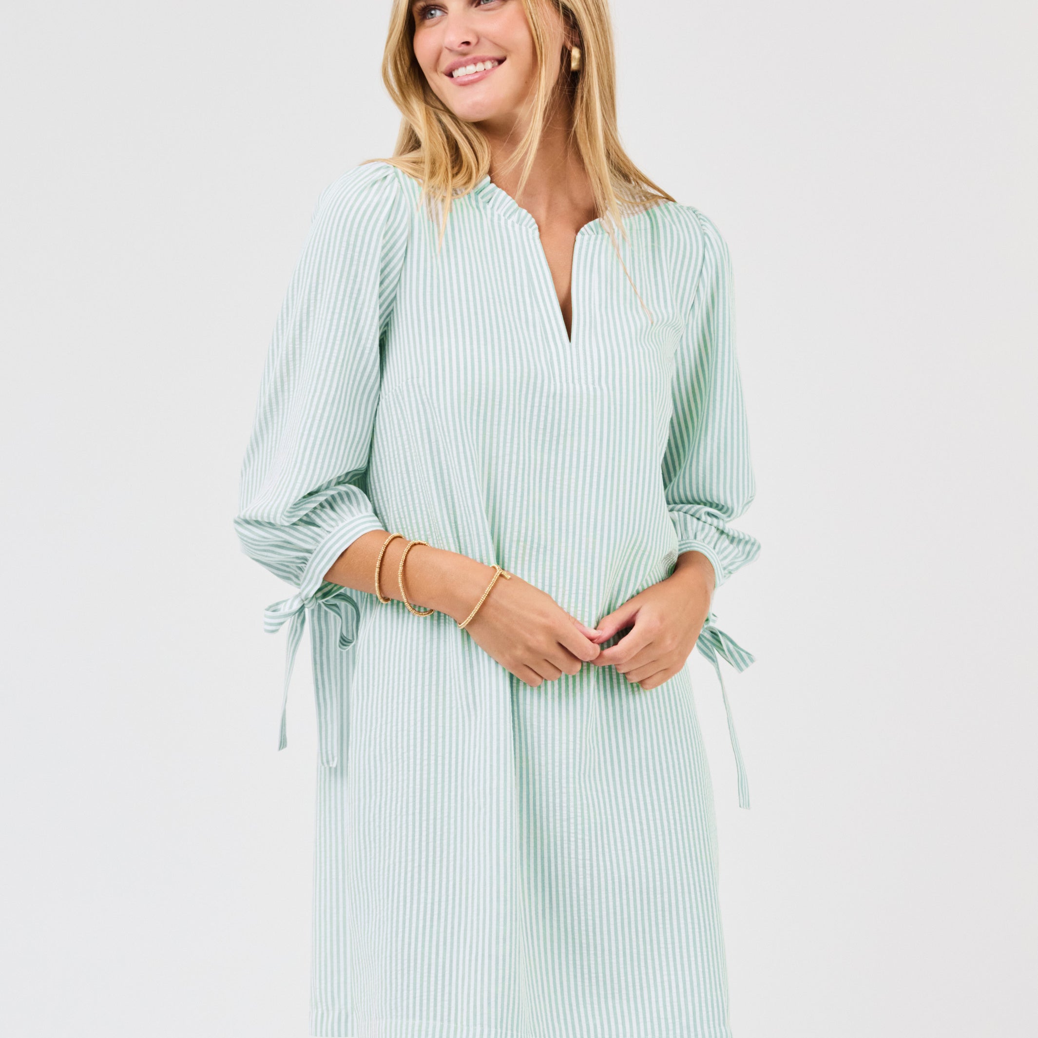 Woman wearing a light green striped dress on a white background