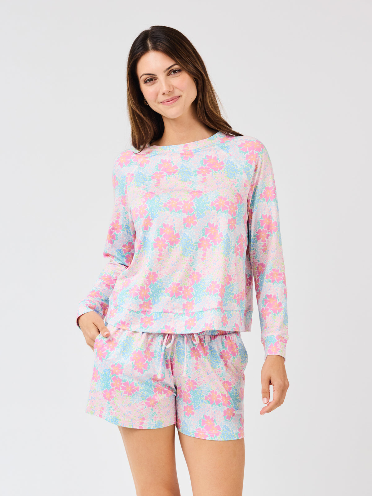 Woman wearing a pastel floral pajama set on a white background