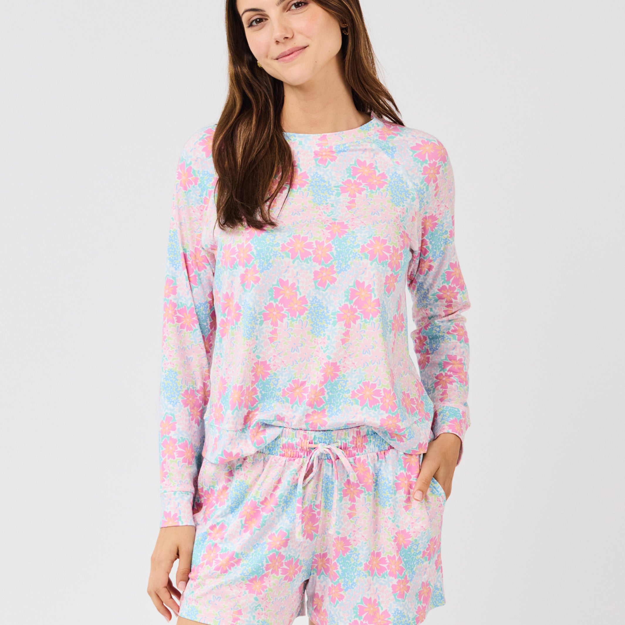 Woman wearing a pastel floral pajama set on a white background