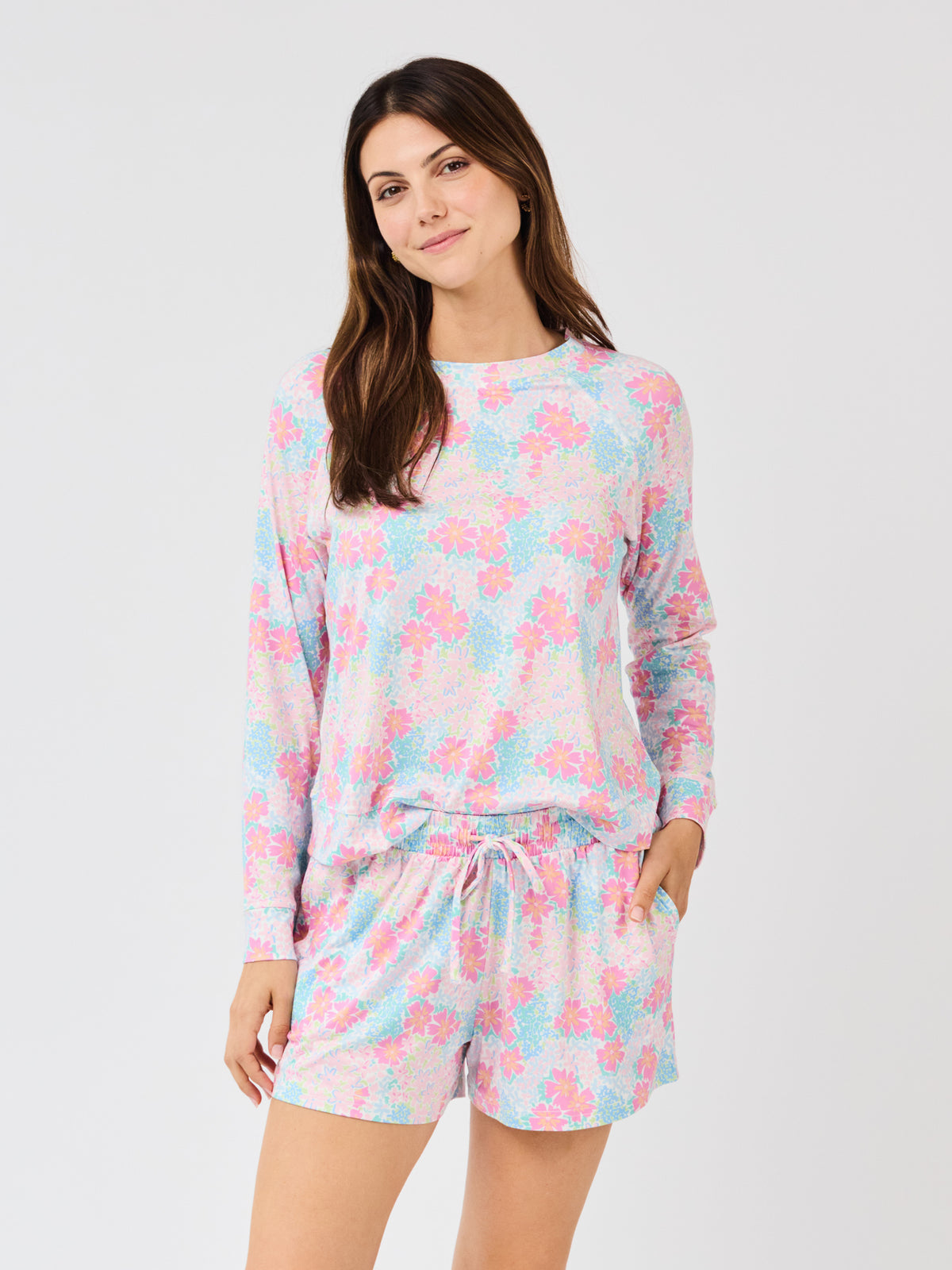 Woman wearing a pastel floral pajama set on a white background