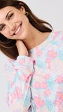 Woman wearing a pastel floral pajama top against a plain background