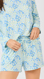 Person wearing a blue and green floral pajama set on a plain background