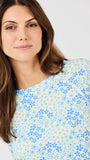 Woman wearing a floral patterned top against a plain background