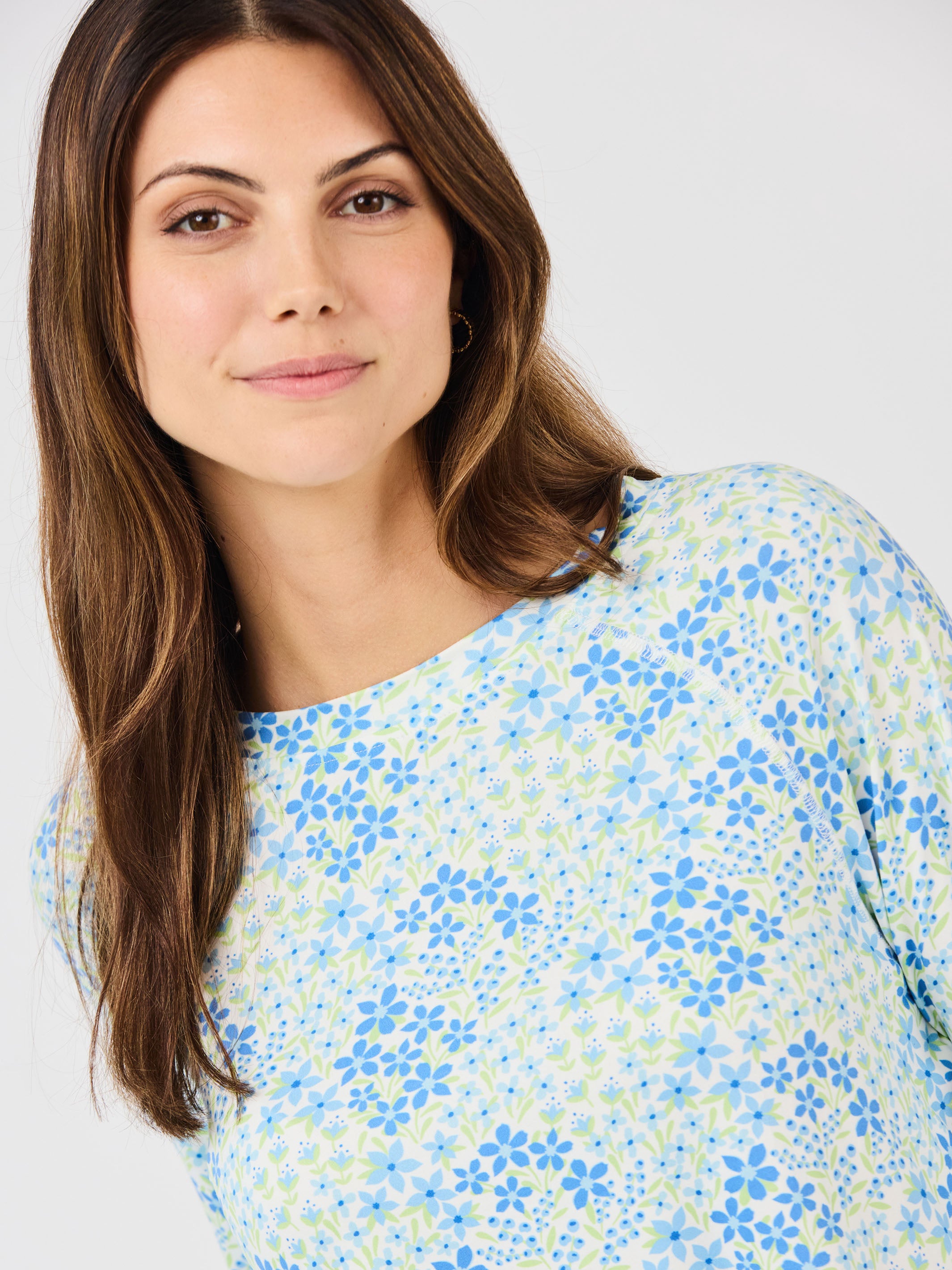 Woman wearing a floral patterned top against a plain background
